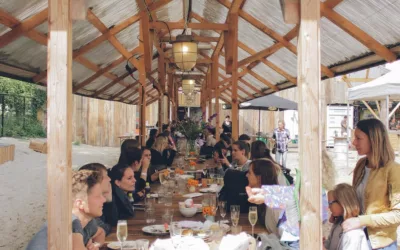 lange houten tafel vol mensen die samen eten